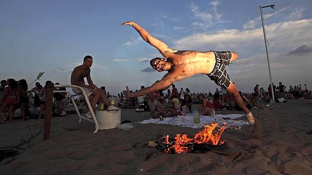 Un joven salta la tradicional hoguera de la Noche de San Juan en la playa de la Malvarrosa de Valencia