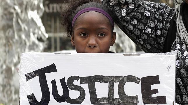 Una menor muestra una pancarta en la que se lee «Justicia»