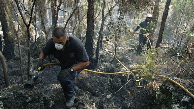 Un retén sofoca algunos rescoldos, en la zona de La Florida, en Tenerife, durante un incendio desatado en 2007