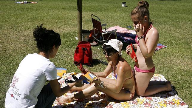 Una chica de Cruz Roja informa sobre los peligros de exposición al sol