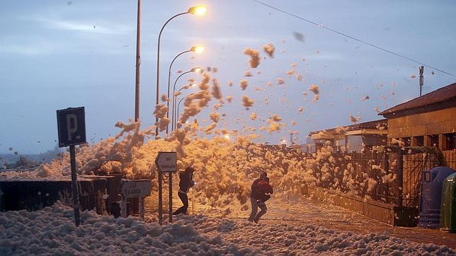 Varias personas se protegen de la espuma del mar en A Guarda