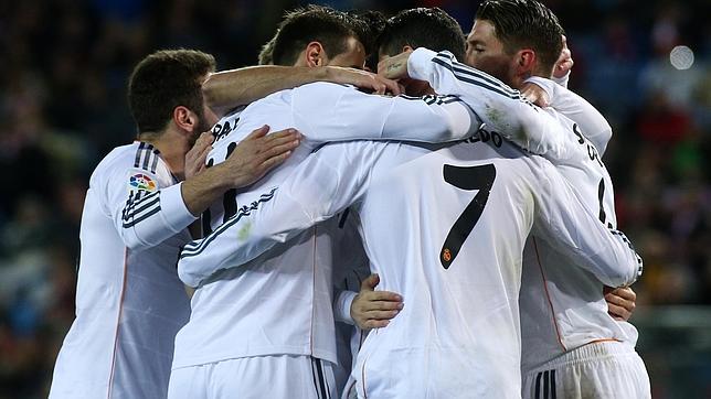 Piña de los jugadores del Madrid celebrando un tanto en el derbi copero