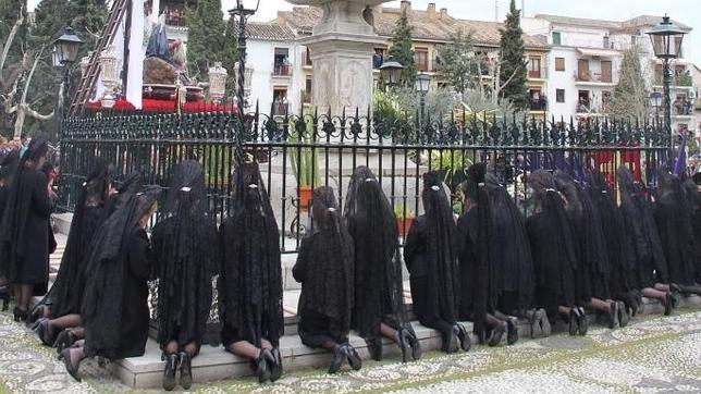 Mujeres vestidas de mantilla piden tres favores al crucificado de piedra de los Favores