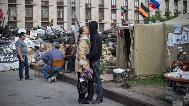 Un pareja se besa junto a una barricada levantada cerca de un edificio regional tomado en Donetsk (Ucrania)