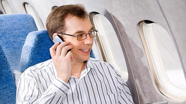 Un hombre habla por teléfono en un avión