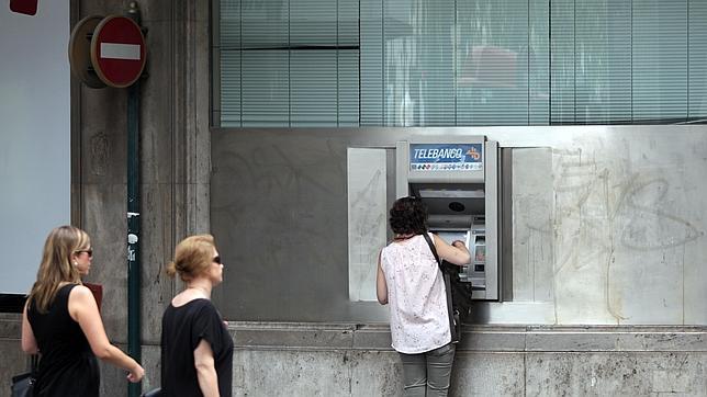 Una mujer saca dinero de un cajero automático
