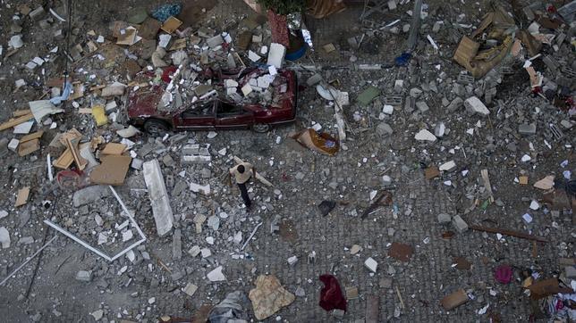 Palestino cruza la calle entre los restos de una de las casas destruidas por los cohetes israelíes en la franja de Gaza