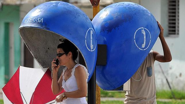 Dos cubanos hablan desde un teléfono público en Santa Clara