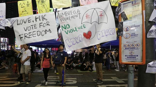 Un cartel con un dibujo de un paraguas con los caracteres chinos «paz» se muestra en una manifestación mientras los manifestantes bloquean la carretera principal en el distrito comercial de Causeway Bay en Hong Kong