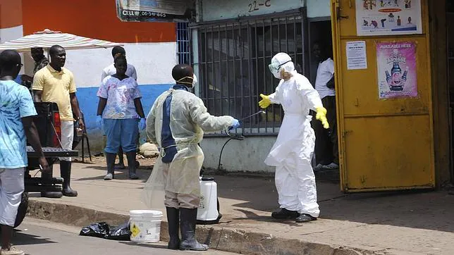 Un miembro de un equipo de enterramiento rocía a un colega con desinfectante en Monrovia, Liberia