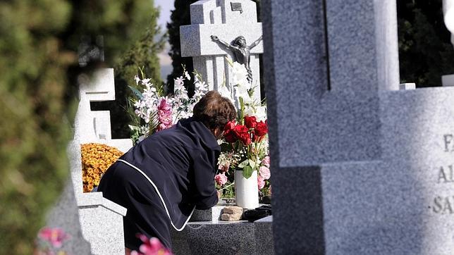 Una señora deposita flores en la tumba de un familiar en el cementerio de Toledo