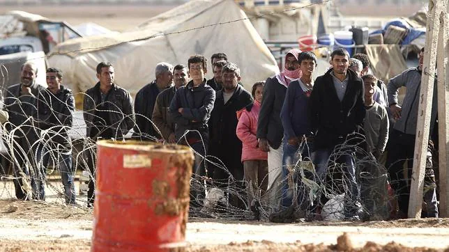 Refugiados sirios esperan para cruzar la frontera y pasar a Turquía cerca de Kobane (Siria)