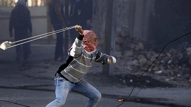 Un manifestante lanza piedras contra la policía israelí en la ciudad cisjordana de Hebrón