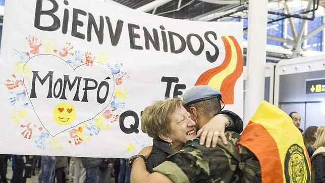 Un soldado se abraza al llegar al aeropuerto de Zaragoza, ante una pancarta de bienvenida
