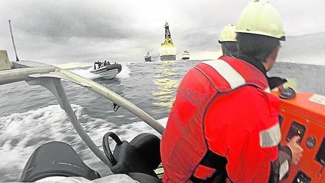 Dos activistas de Greenpeace en una de sus lanchas y otra de la Armada española acercándose por la izquierda, durante la protesta frente a la plataforma Rowan Renaissance contra las prospecciones petrolíferas de Repsol en aguas de la isla de Fuerteventura