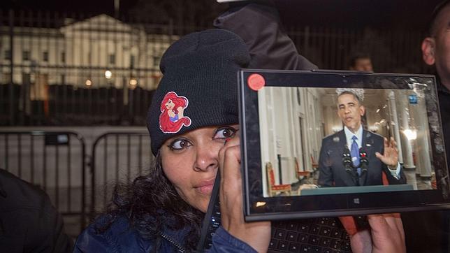 Una mujer escucha a Barack Obama a través de una «tablet» frente a la Casa Blanca