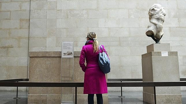 Una visitante lee la nota explicativa junto al pedestal de una escultura sin cabeza del dios fluvial Ilisós en el Museo Británico