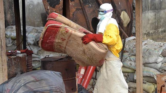 Un sanitario desecha un colchón en un centro de tratamiento del ébola en Conakry