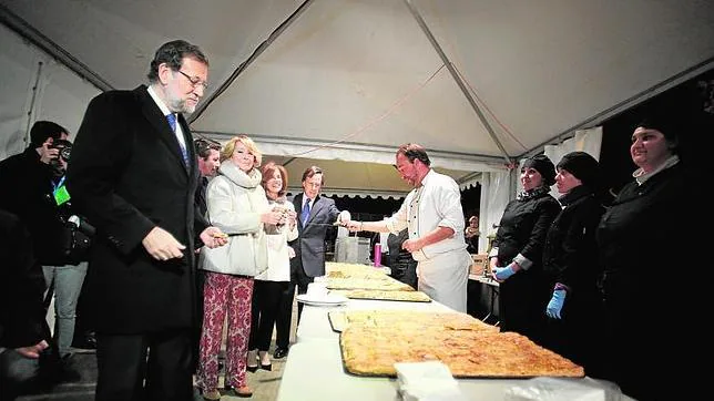 Rajoy y Aguirre, en un primer plano a la izquierda, cogiendo empanada para su cena navideña