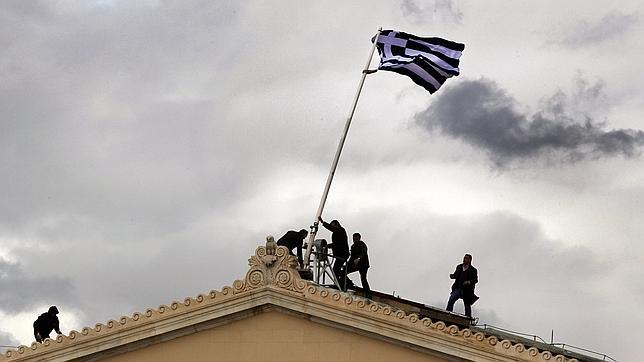 Empleados levantan la bandera griega en lo alto del Parlamento en Atenas