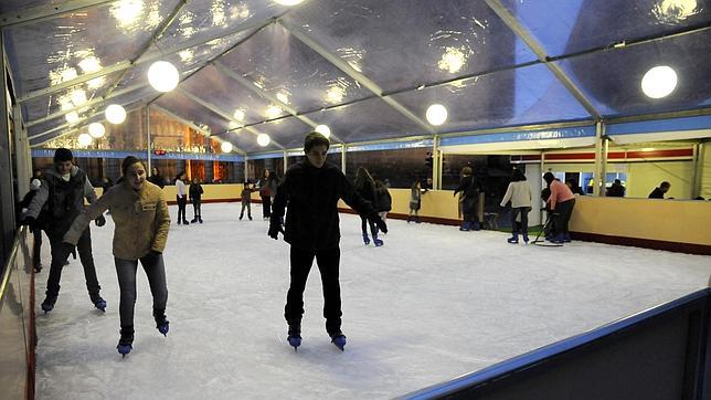 Unos niños patinan sobre hielo en la pista de patinaje instalada en la plaza del Ayuntamiento