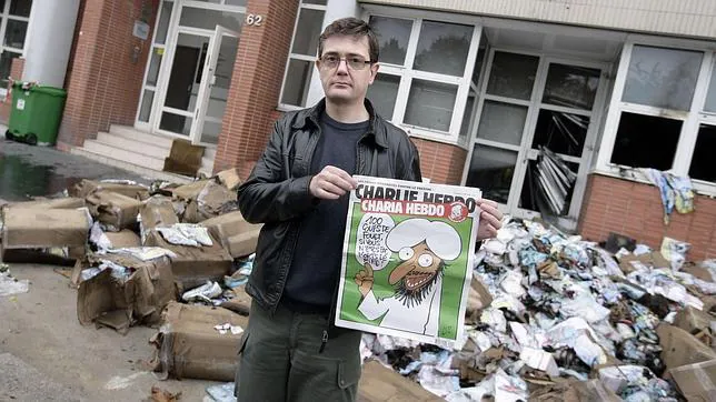 El director de «Charlie Hebdo», Charb, con un polémico ejemplar ante las oficinas atacadas con cócteles molotov en 2011