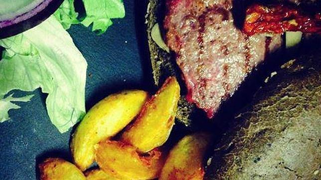 Detalle de la amburguesa con champiñón rehogado con ajo, tomate seco en pan negro del restaurante Perro flaco