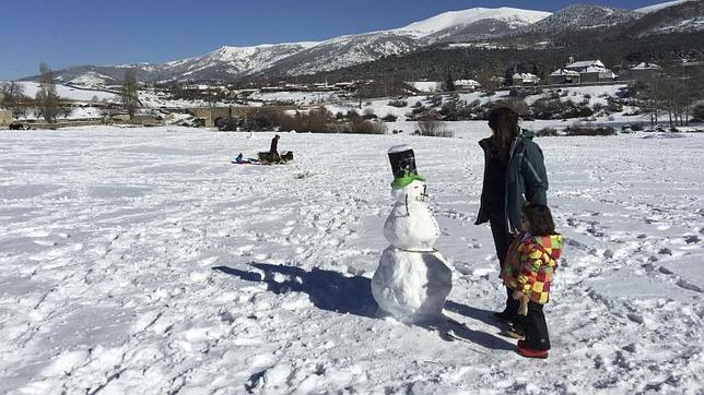 Una mujer y una niña contemplan un muñeco de nieve este sábado en Valsaín (Segovia)