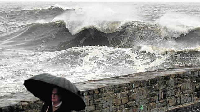 Un hombre pasea junto a la playa de la Zurriola de San Sebastián, donde esta activada la alerta naranja por la llegada de un fuerte temporal con olas de siete metros de altura.