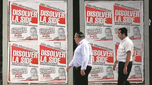 Dos hombres pasan junto a carteles que piden que se aclare la muerte del fiscal Nisman, en Buenos Aires