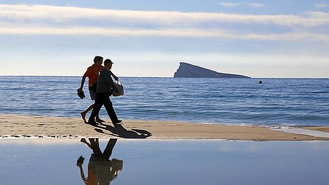 Dos personas pasean por la playa de Levante de Benidorm