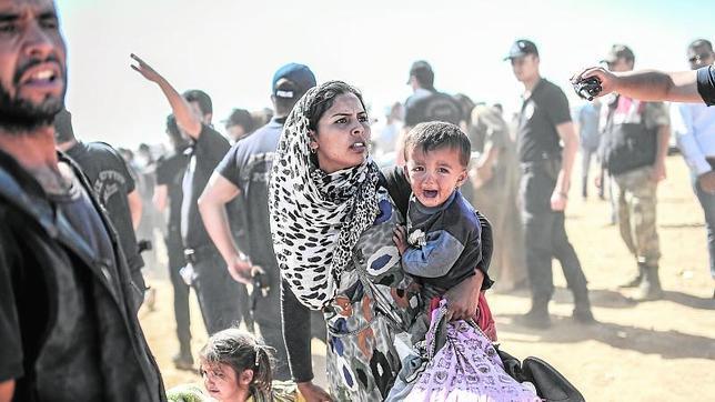Una de las imágenes del año de AFP, en la que se puede ver a una mujer kurda con sus hijos, atravesando la frontera turco-siria