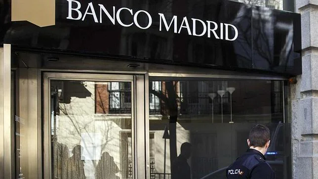 Un policía custodia una sede de Banco Madrid.