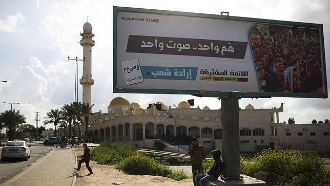 Niños juegan junto a un cartel de la campaña electoral