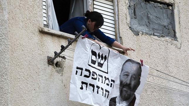 Una mujer cuelga una pancarta en apoyo al partido shas