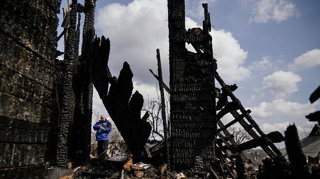 Un observador internacional de la OSCE inspecciona los restos de una casa quemada en la ciudad de Donetsk