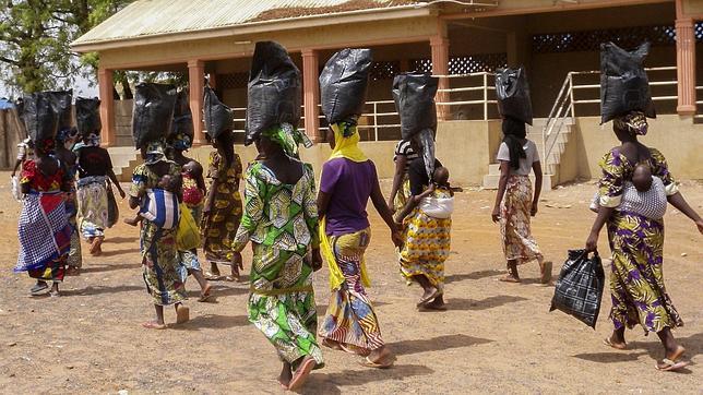 Desplazadas internas nigerianas, que huyeron de áreas de conflicto apoderadas por el grupo yihadista Boko Haram, cargan comida mientras salen de una sesión de oración especial por las adolescentes secuestradas por la organización