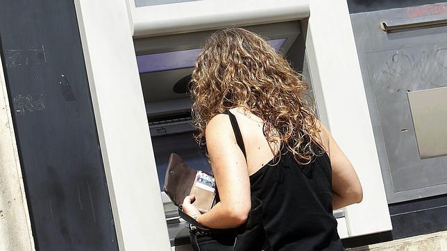 Una clienta, sacando dinero de un cajero automático