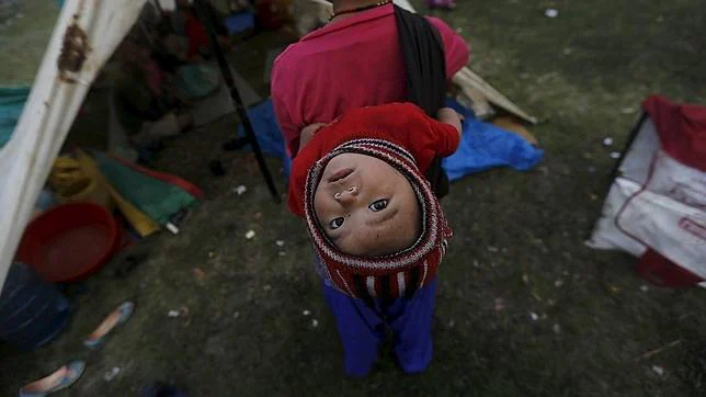 Una madre con su hijo, víctimas del terremoto de Nepal, frente a su refugio en Katmandú