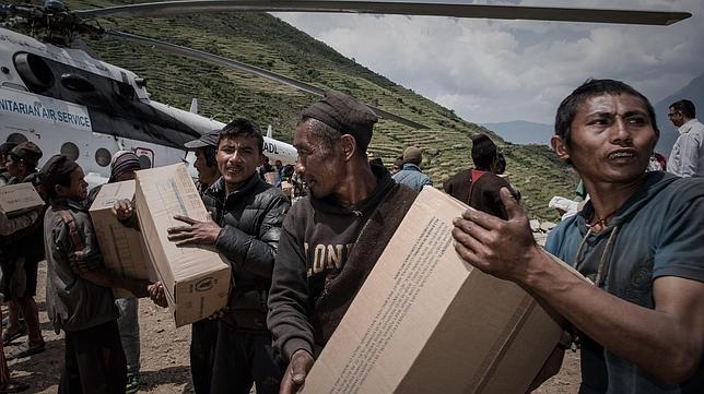 voluntarios descargan suministros de socorro en la remota aldea del distrito de Gorkha Kerauja de Nepal