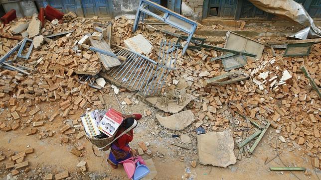 Una mujer nepalí traslada sus pertenencias un día después del nuevo terremoto, en Chautara, Nepal