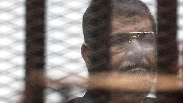 Mohamed Mursi mira tras los barrotes de una celda en el tribunal que ha dictado su sentencia de muerte