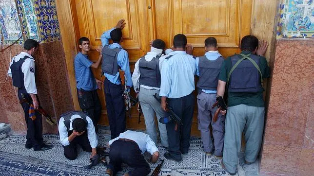 Policías iraquíes chiíes rezan junto a la puerta de una mezquita de Nayaf
