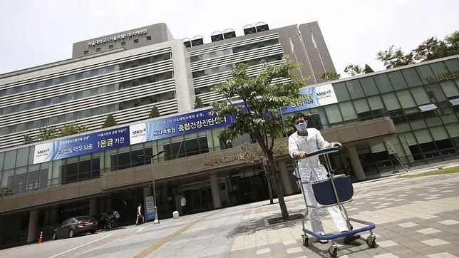 Un paciente pasea junto a un hospital con una máscarilla en Seúl