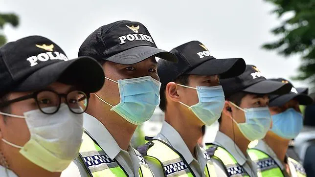Policías surcoreanos con medidas de protección frente al virus, este lunes