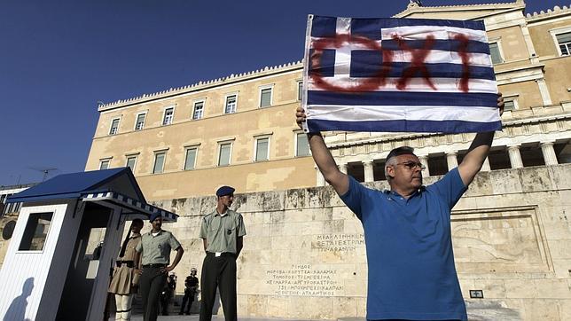Un hombre exhibe un «no» en la bandera nacional, junto al edificio del Parlamento en la plaza Syntagma de Atenas