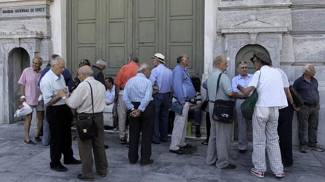 Un grupo de pensionistas hace cola para poder sacar su dinero