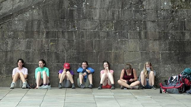 Un grupo de peregrinos descansa al pie de las escaleras de la Catedral de Santiago