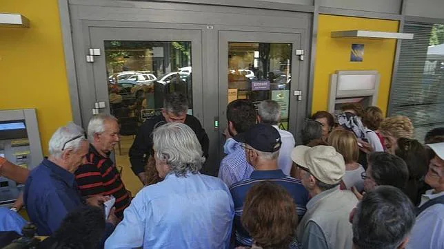 Pensionistas hacen cola para retirar dinero a la entrada de una sucursal bancaria en Salónica, Grecia