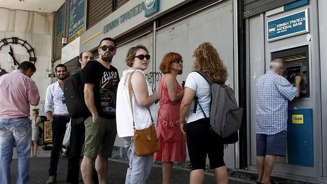 Atenienses hacen cola para retirar dinero de un cajero automático en una sucursal del Banco Nacional de Grecia